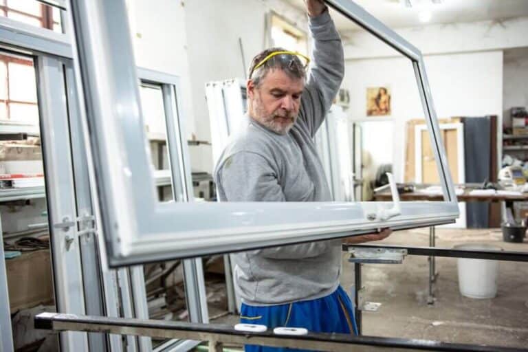 Pracownik trzymający ramę okienną w warsztacie