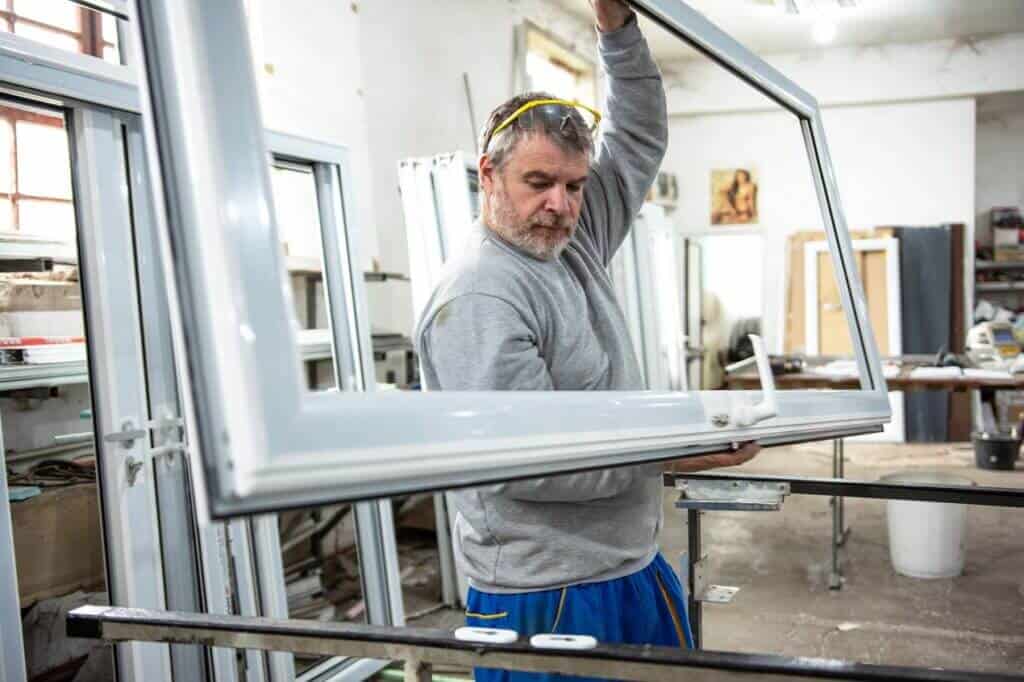 Pracownik trzymający ramę okienną w warsztacie