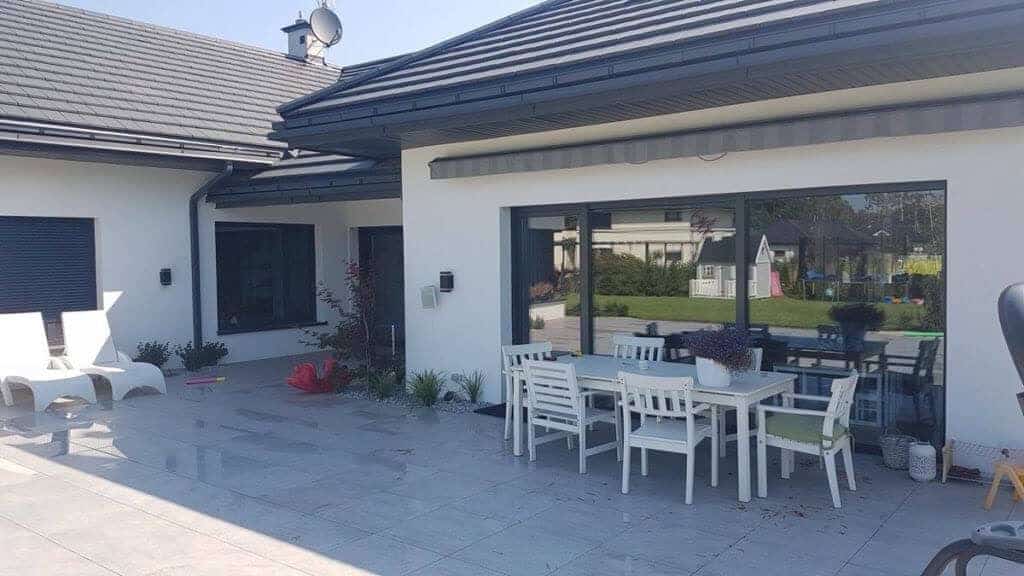 Parterowy dom z przestronnym tarasem i dużymi drzwiami przesuwnymi Schüco