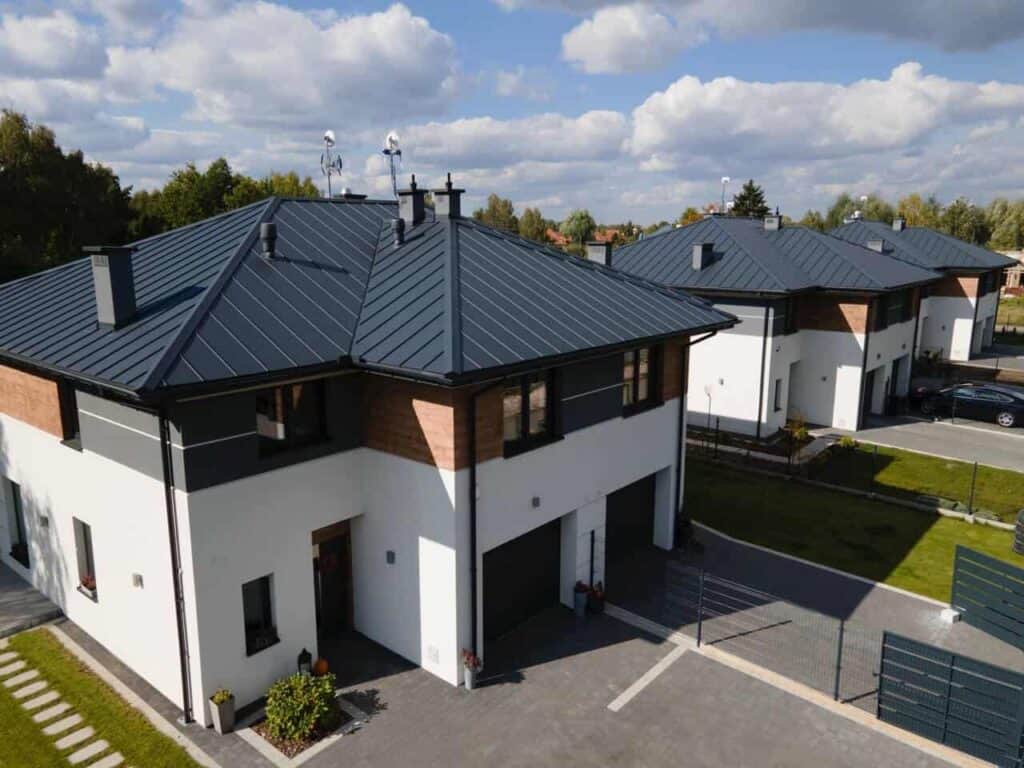 Widok z góry na nowoczesne osiedle domów bliźniaczych z ciemnymi dachami