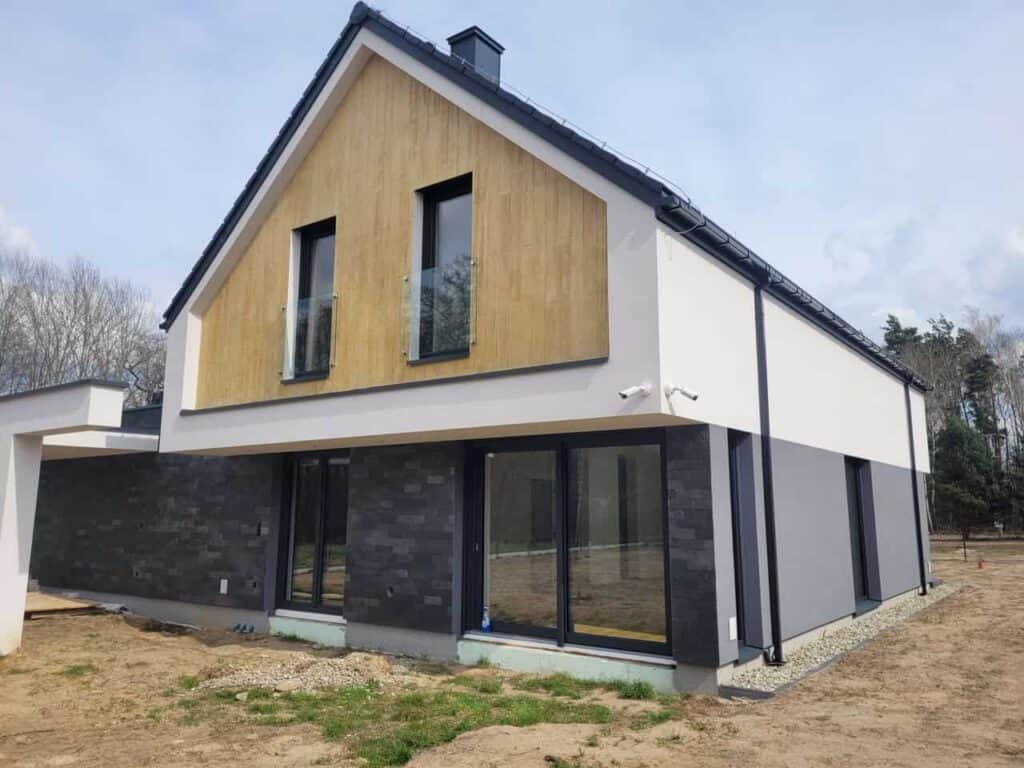 Duże przesuwne drzwi tarasowe i balkony z czarną stolarką Schüco – dom jednorodzinny
