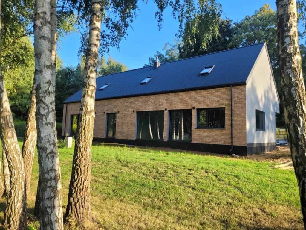 Nowoczesny dom z ceglaną elewacją i oknami PCV Schüco – widok z boku